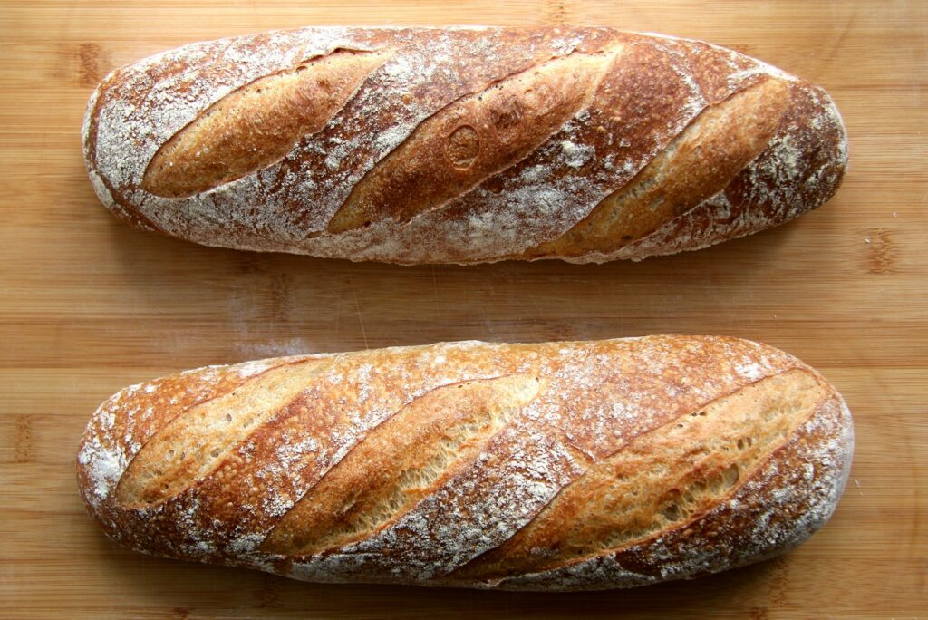 Two crusty artisan loaves of bread on a wooden table
