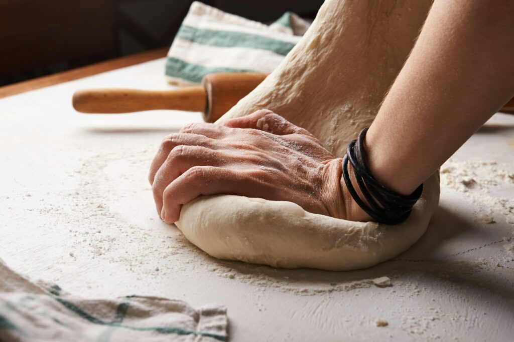 Baker kneading dough by hand on a floured surface