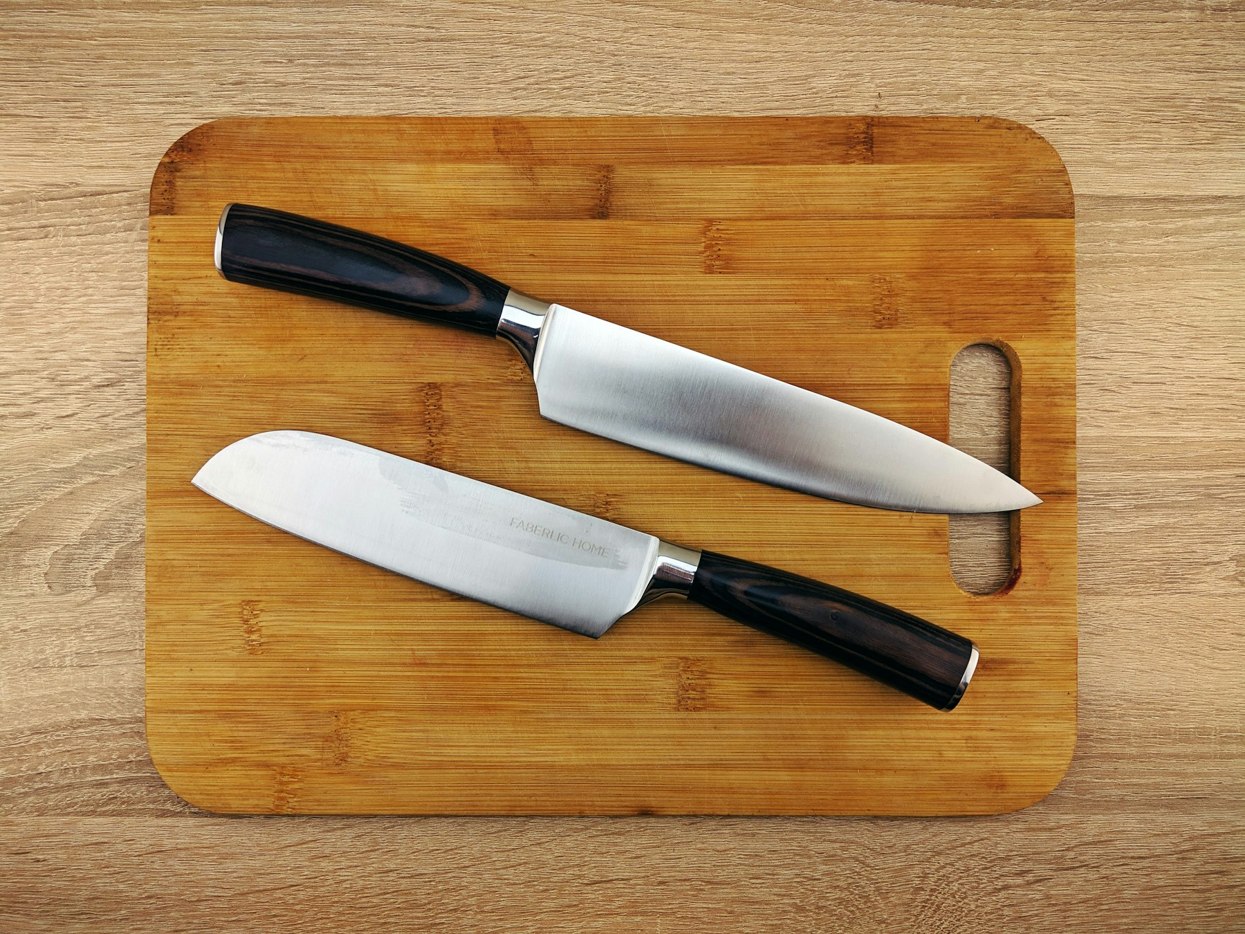 Two chef knives resting on a wooden cutting board