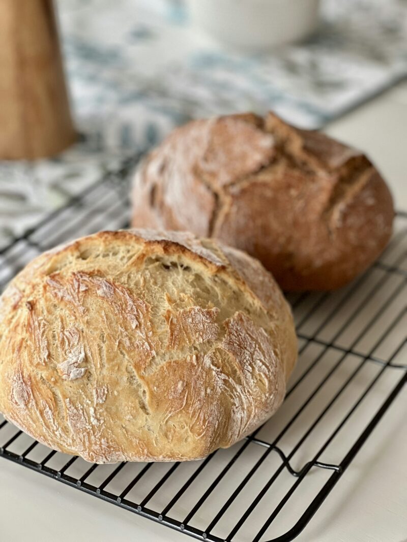 Two crusty artisan loaves cooling on a rack