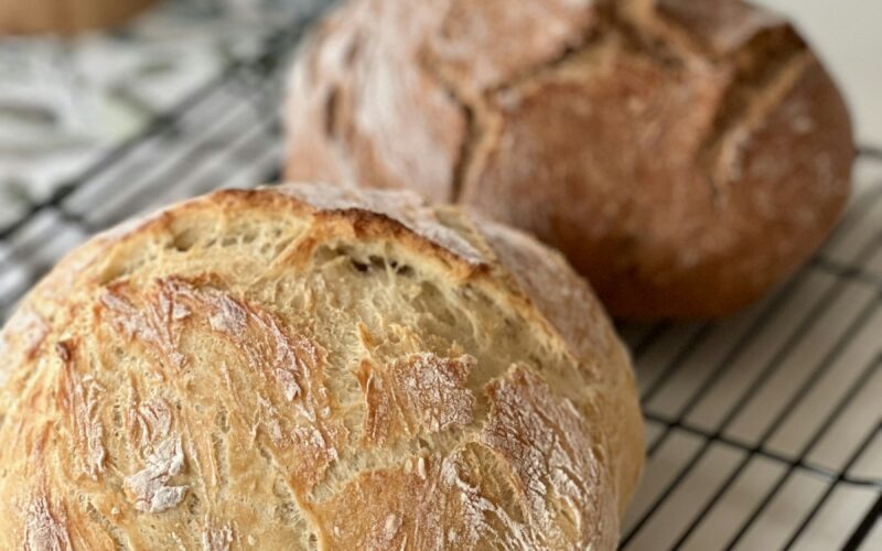 Two crusty artisan loaves cooling on a rack