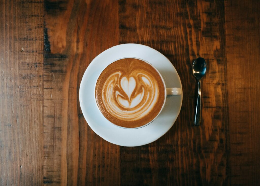 Latte with leaf latte art in a white cup on a wooden table