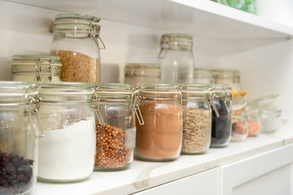 Pantry shelf with glass jars of flour, grains and spices
