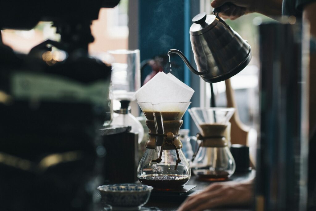 Barista brewing pour-over coffee with a gooseneck kettle