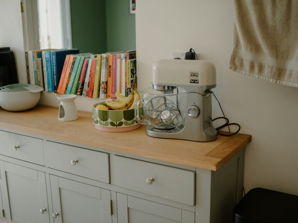 Stand mixer on a kitchen counter beside cookbooks and a fruit bowl